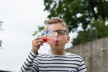 Jugendlicher / Kind / Heranwachsender pustet mit Seifenblasen