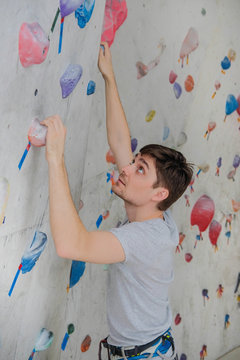 A successful man climbing on climbing wall. Teenage rock climber on boulders.