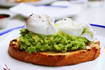 Poached egg with avocado on white plate