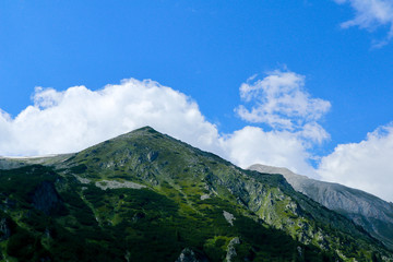 Beautiful view on the high green mountains peaks, on the blue sky background. Mountain hiking paradise landscape, no people.