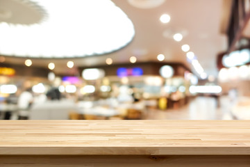 Wood table top on blur background of food court in shopping mall