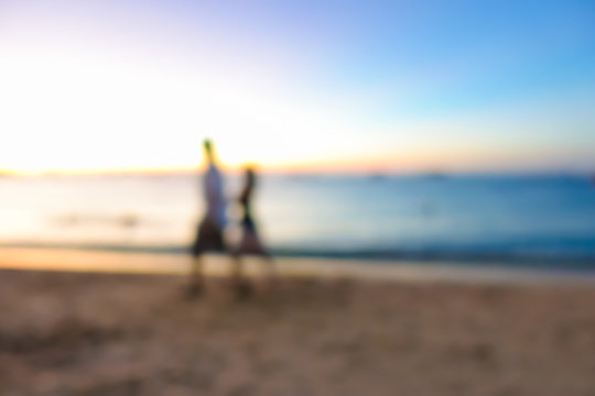 Blur image of couple walking at the beach in twilight