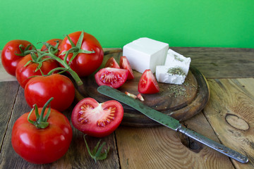 Red cherry tomatoes on a wooden table on a background of a green wall