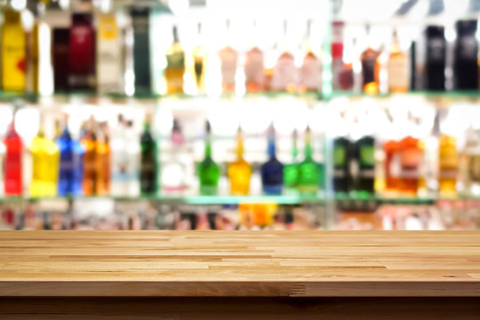 Wood bar top on blur colorful alcohol drink bottle background