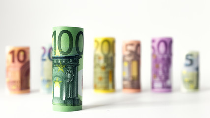 Gerollter 100 Euro Schein mit anderen Geldscheinen im Hintergrund