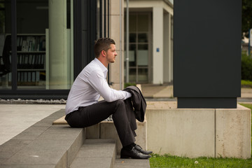 Business Mann sitzt auf Treppe und wartet / Pause / Termin / Kalender