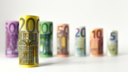 Gerollter 200 Euro Schein mit anderen Geldscheinen im Hintergrund