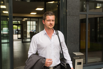 Business Mann / Herr verlässt Arbeitsgebäude / Feierabend / Termin
