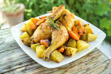 Piatto di pollo arrosto con contorno di patate e carote al forno