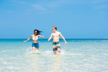 Couple running in seawater at the beach