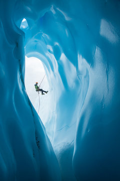 Man Rappelling past opening of blue ice cave on Matanuska Glacier, Alaska