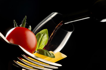 fork with pasta and glassof wine on black bacground