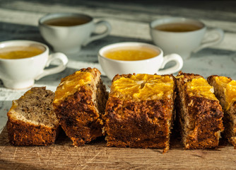 Homemade vegan banana and orange cake with coconut flour with four whire cups on the background