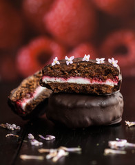 Homemade vegan rice flour chocolate cakes with raspberry jam and coconut cream filling, covered with dark chocolate and decorated with lilac flowers. 