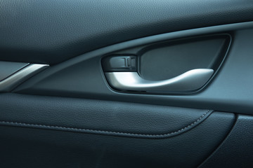 close up. car leather interior detail of door handle and lock upside it. 