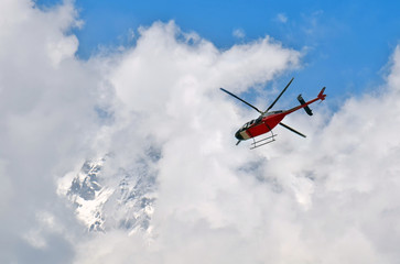 Fototapeta na wymiar Helicopter in the cloudy sky and mountain. Himalayan Mountains, Annapurna National Park.