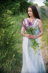 Young beautiful romantic woman in a dress with a bouquet of wildflowers