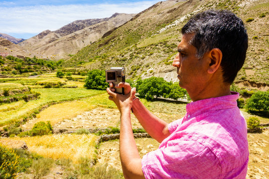 Closeup of a tourist filming and taking photos of a valley in the Atlas mountains. 