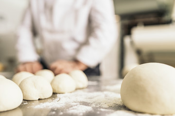 Baker kneading dough in a bakery.