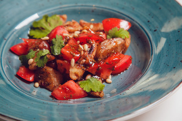 Salad with tomatoes and pieces of fried meat.