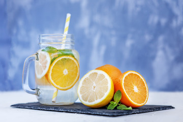 Refreshing lemonade with lemon, orange and mint. Glass jar and tubule. Vitamins. The concept is summer, diet, vegetarian, fitness, healthy eating and lifestyle.