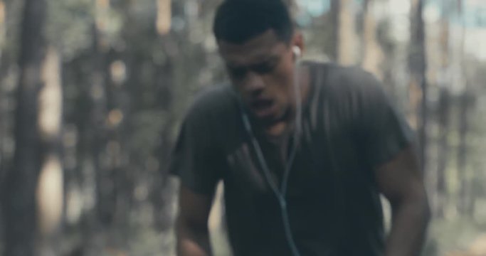 Young fit African American sweating while catching breath after sprinting on the forest road. 4K UHD