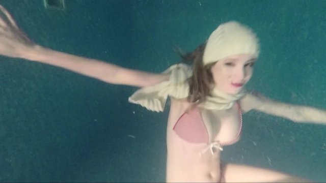 Slow movement of a slender girl in a bikini floating under the water.