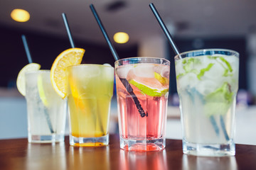 Glasses of cold refreshing drink with fruits and ice on a table. Summer lemonade.