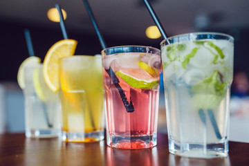 Glasses of cold refreshing drink with fruits and ice on a table. Summer lemonade.