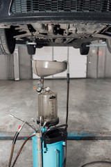 The image of tank for used crankcase oil. the car on the lift