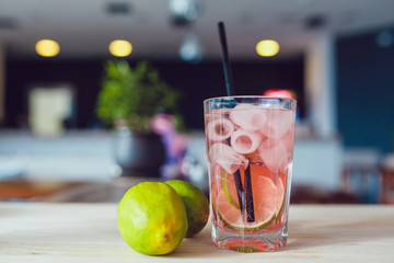 Glass of cold refreshing drink with fruits and ice on a table. Summer lemonade.