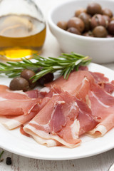 smoked meat with olives on white plate