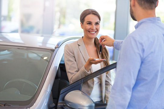 Woman receiving keys from a car dealer
