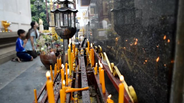 Candles in Thai Temple and people are praying and merit making as background