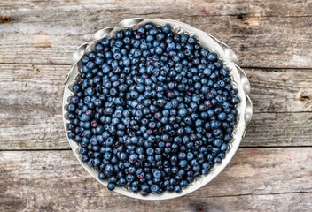 Fresh blueberries in basket on old table, ripe fruits from forest on farmer market, overhead