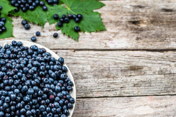 Fresh blueberries in basket on wooden table, ripe fruits from forest on farmer market, copy space, top view