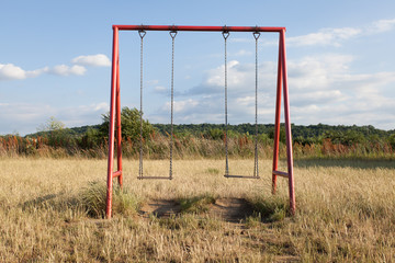 Fototapeta na wymiar two swings on a red frame