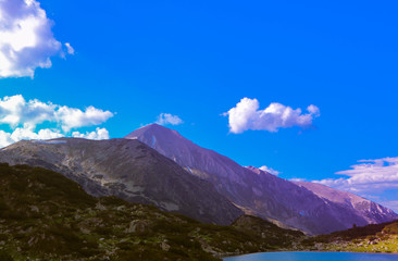 Beautiful mountains lake with a reflection of the high green mountains peaks, on the sunset sky background. Amazing Mountain hiking paradise landscape with a lake.