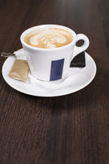 Cup of coffee with beautiful latte art. Tasty cup of coffee on wooden background with beautiful latte art.