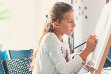 Young girl drawing on a canvas with easel