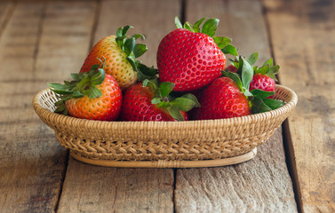Fresh strawberries on wood background. Ripe strawberry in basket on rustic wood  table. Copy space background of strawberry for your design. Natural tone style fruit  concept background or wallpaper..