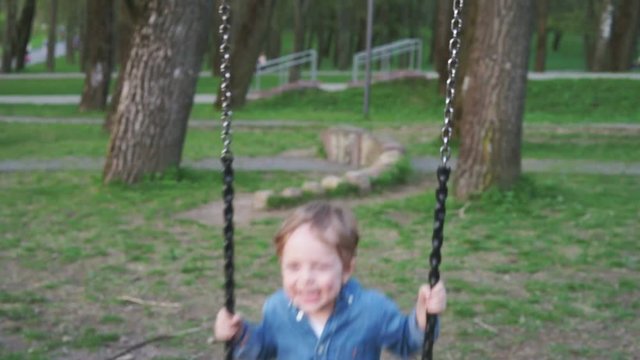 Caucasian boy swinging on a swing and laughing. 