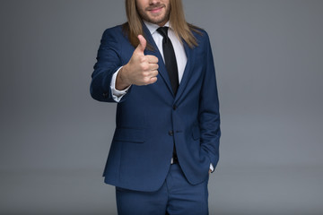 Cropped shot of handsome young man in suit showing thumb up sign