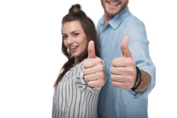 Close-up view of happy young couple standing together and showing thumbs up sign