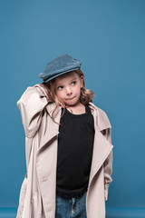 Cute little girl in cap looking away isolated on blue