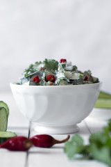 Cucumber salad with yogurt dressing and hot pepper on the white background