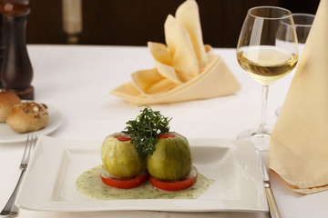 Stuffed zuchini arranged on a plate, Wineglass in the background, Traditional dish in elegant setting, Selective focus with soft light