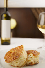 Cheese puff pastry arranged on a plate, Wine bottle and wineglass in background, Traditional dish in elegant setting, Selective focus with soft light