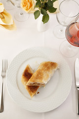 Apple pie slice arranged on a plate, Wineglass in background, Traditional dessert in elegant setting, Selective focus with soft light