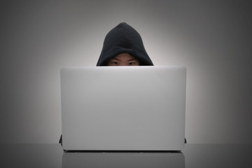 woman wearing hood hacking information from laptop